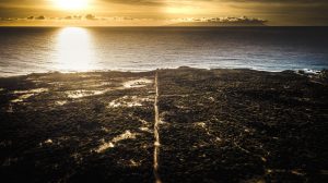Aerial view of clear line path road on the outdoor nature to the ocean with golden sunset